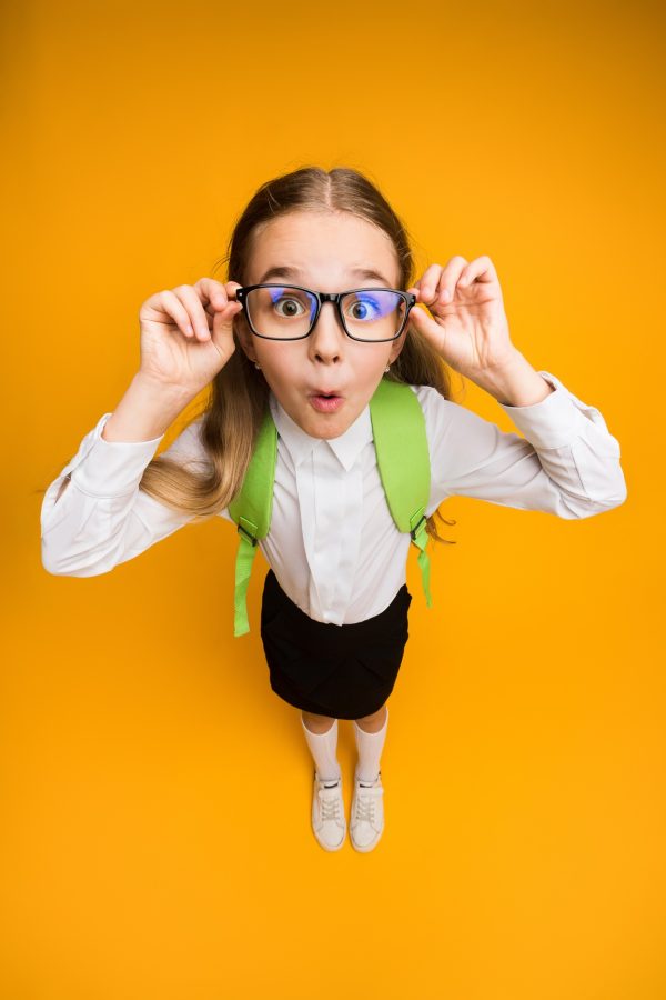 Funny Nerdy Schoolgirl In Eyeglasses Looking At Camera, Yellow Background